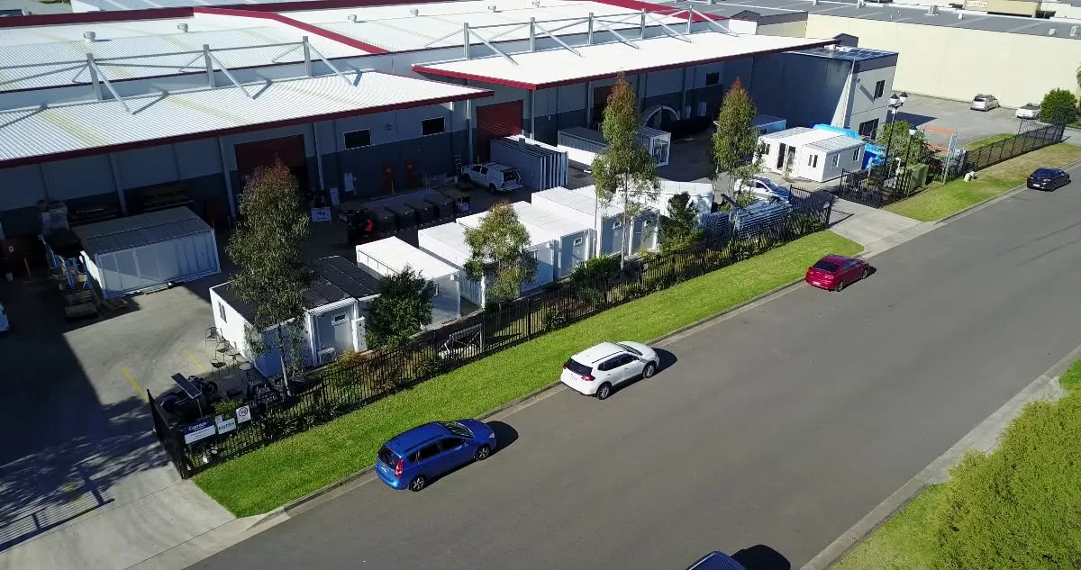 Aerial view of the yard: modular container units, offices and storage containers laid out beside the fabrication building
